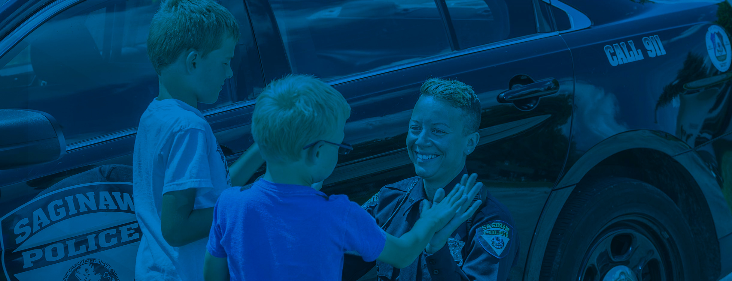 Officer Samm Buth with two children by her police vehicle.